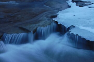 Obraz premium Long exposure of river water with ice, winter concept