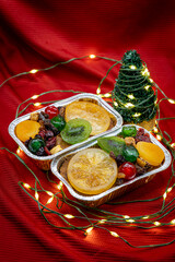 Rum Fruitcake with garland light on red fablic background. Christmas tree Holliday cake