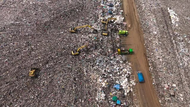 Aerial top view of A Huge Waste, garbage, dump, rubbish landfill. A landfill compactor, group of workers sort out the garbage in the landfill. Trash trucks dump waste polluting products.
