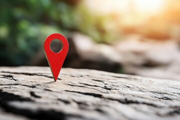 A vibrant red location pin stands prominently on a weathered wooden surface, symbolizing exploration and adventure in nature.
