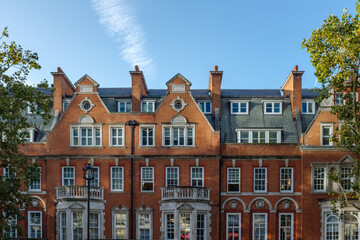 Elegant red brick building facade with white trim and slate roof in london
