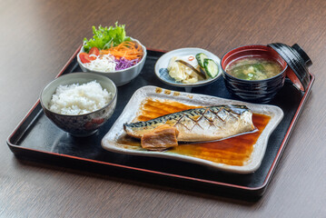 A delicious Japanese meal with grilled fish, rice, miso soup, and salad.