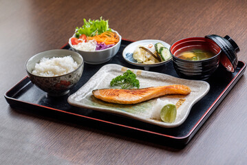 A delicious and healthy Japanese meal with grilled salmon, rice, salad, and miso soup.