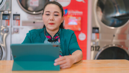 Woman sits at laundromat, focused on her tablet setting combines modern technology with everyday routine of laundry, blend of life and convenience