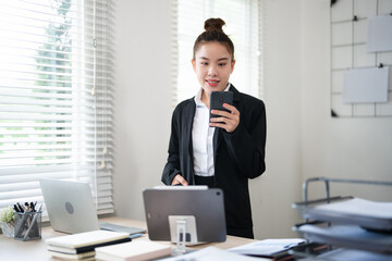 Young busy business woman talking on phone working in modern office. Asian businesswoman company...