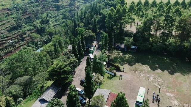 A green mountainous area with a villa, as several buses prepare to leave the premises. Perfect for travel, tourism, or real estate projects showcasing scenic landscapes and group activities