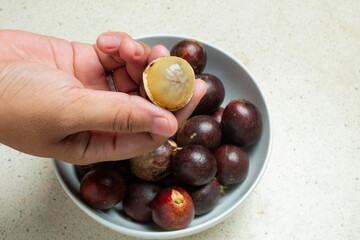 open hands showing open fruit from its skin, namely matoa fruit or betel nut, sweet fruit, like langsat fruit
