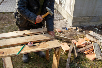 A man is hammering a piece of wood