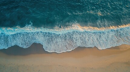 A serene top-down view of a sandy beach meeting the ocean, with waves gently washing ashore