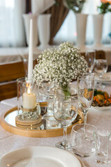 A table in a restaurant with candles. A candle is burning on the table with food.