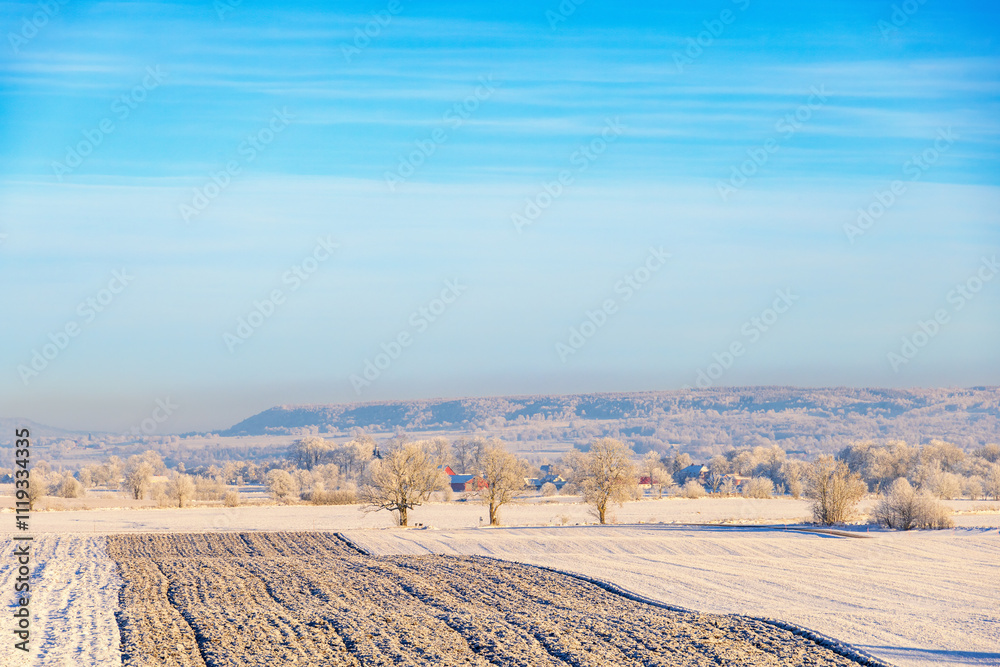 Wall mural Wintry rural landscape view with a plowed field a cold sunny winter day