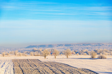 Wintry rural landscape view with a plowed field a cold sunny winter day