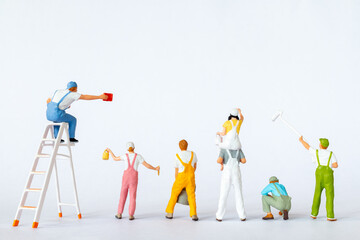 A group of colorful miniature figures dressed as painters in overalls on a clean white background,...