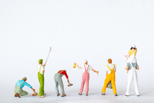 A group of colorful miniature figures dressed as painters in overalls on a clean white background, ideal for concepts like teamwork, renovation, or creative projects.