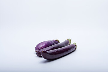 Fresh purple eggplant cut into pieces and whole photographed against a white background
