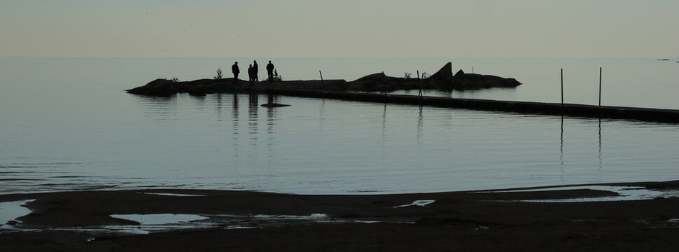 Outlines of people and a rock formation at the shore of Lake Vanern, Vita Sandar, Mellerud, Sweden.