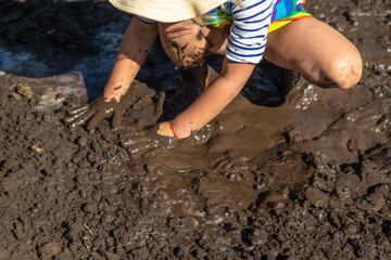 Child playing in mud. Selective focus.