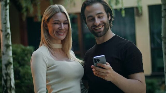 A couple holds a phone, looking at the screen. They can't believe they won a prize so easily in a mobile app. Surprised, they don't show the phone to the camera. They are very happy about winning.