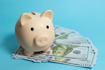 Piggy bank on hundred dollar bills on a blue isolated background, finance and savings concept