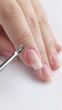 A woman removes the cuticles of the nail with a metal tool. Healthy nails. Manicure. 