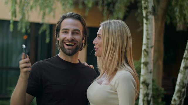 The pair views their smartphone, thrilled by a prize won through a mobile app. Overjoyed, they smile wide at the green screen, celebrating their success and enjoying the surprise victory together.