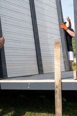 Installing a wall of wooden planks painted white in a gazebo.