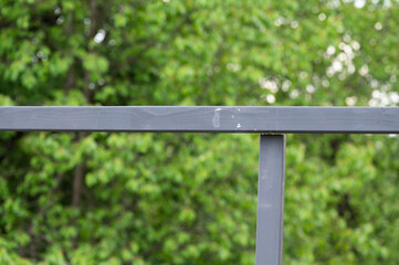 Two wooden beams are placed at right angles against a background of trees.