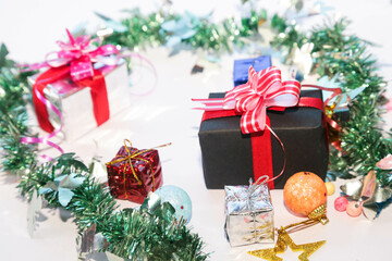 Season's greetings scene. Christmas decorations,gift boxes with red ribbons, сhristmas balls,  rustic star, holly berries, frosty spruce branches, confetti on white backdrop, selective focus with blur