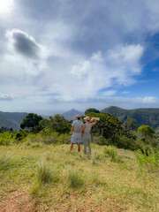 A young couple admiring the stunning view of an ancient tropical mountain forest in Mauritius