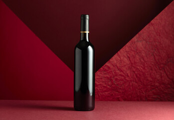 Bottle of red wine on a red background.