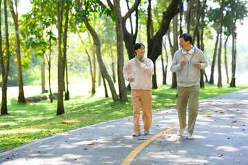 Cheerful middle aged man and his daughter enjoying a light jogging or brisk walking session on park...