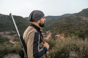 Hunter standing on mountain ridge holding rifle