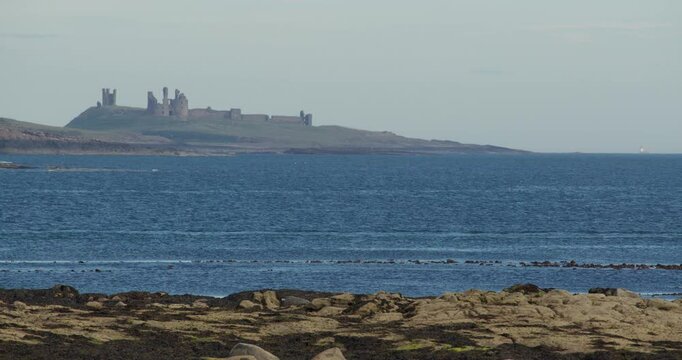 distant shot of an old castle on the Cliff edge at Longhoughton beach of the howdiemony sands. Alnwick