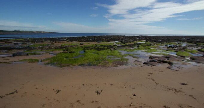 Extra wide shot of seaweed rocks and boulders exposed at low tide at Longhoughton beach of the howdiemony sands. Alnwick
