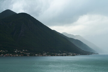 Obraz premium Cloudy mountainside over calm waterscape