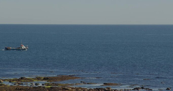 long shot over fishing boats passing through frame at Longhoughton, beach and howdiemony sands, Alnwick
