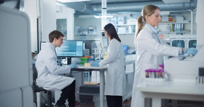 Medical Research Lab: Male Scientist and Asian Female Researches Discussing Experiment Observations. Female Coworker Preparing Samples for Chemical Analysis on a Polymerase Chain Reaction Machine - Powered by Adobe