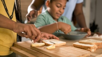 Crop woman applying butter on bread with brother whisking egg yolk in background
