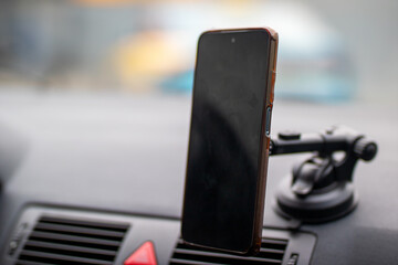 A cell phone is on a suction cup on a cars dashboard