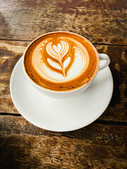 Ceramic cup with Coffee with white cream in Latte art,on wooden desk,