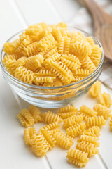 Uncooked italian pasta. Radiatori pasta in bowl on white table.