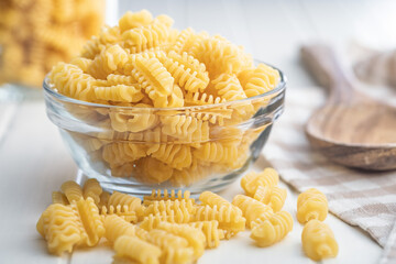 Uncooked italian pasta. Radiatori pasta in bowl on white table.