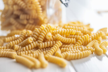 Uncooked italian pasta. Fusilli pasta on white table.
