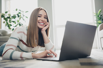 Fototapeta premium Cheerful young woman enjoying leisure time at home, relaxing in a well-lit living room