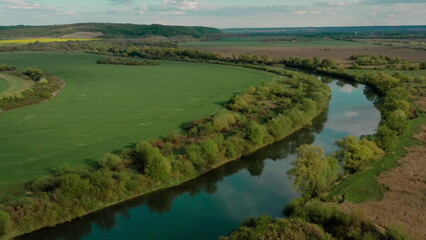 Breathtaking landscape from a height: the river meandering through the fields offers a unique view from a drone. Natural beauty and harmony of water and green spaces.