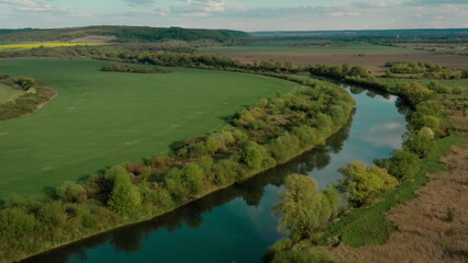 Breathtaking landscape from a height: the river meandering through the fields offers a unique view from a drone. Natural beauty and harmony of water and green spaces.