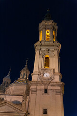 Close-up of one of the impressive towers of the touristy Basilica del Pilar in Zaragoza illuminated at night.