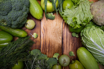Composition of bright and juicy green vegetables, spices and herbs on a wood backdrop