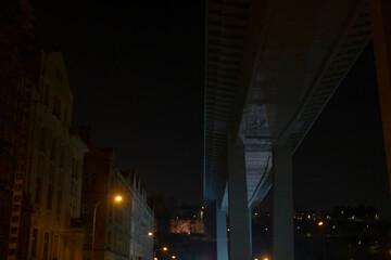 Fototapeta premium A city street illuminated at night featuring a bridge in the background