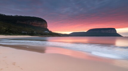 Fototapeta premium Serene sunrise over a tranquil beach with dramatic cliffs reflecting in calm waters.